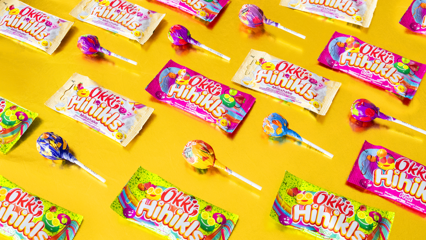 Okki candy products and lollipops on a yellow background