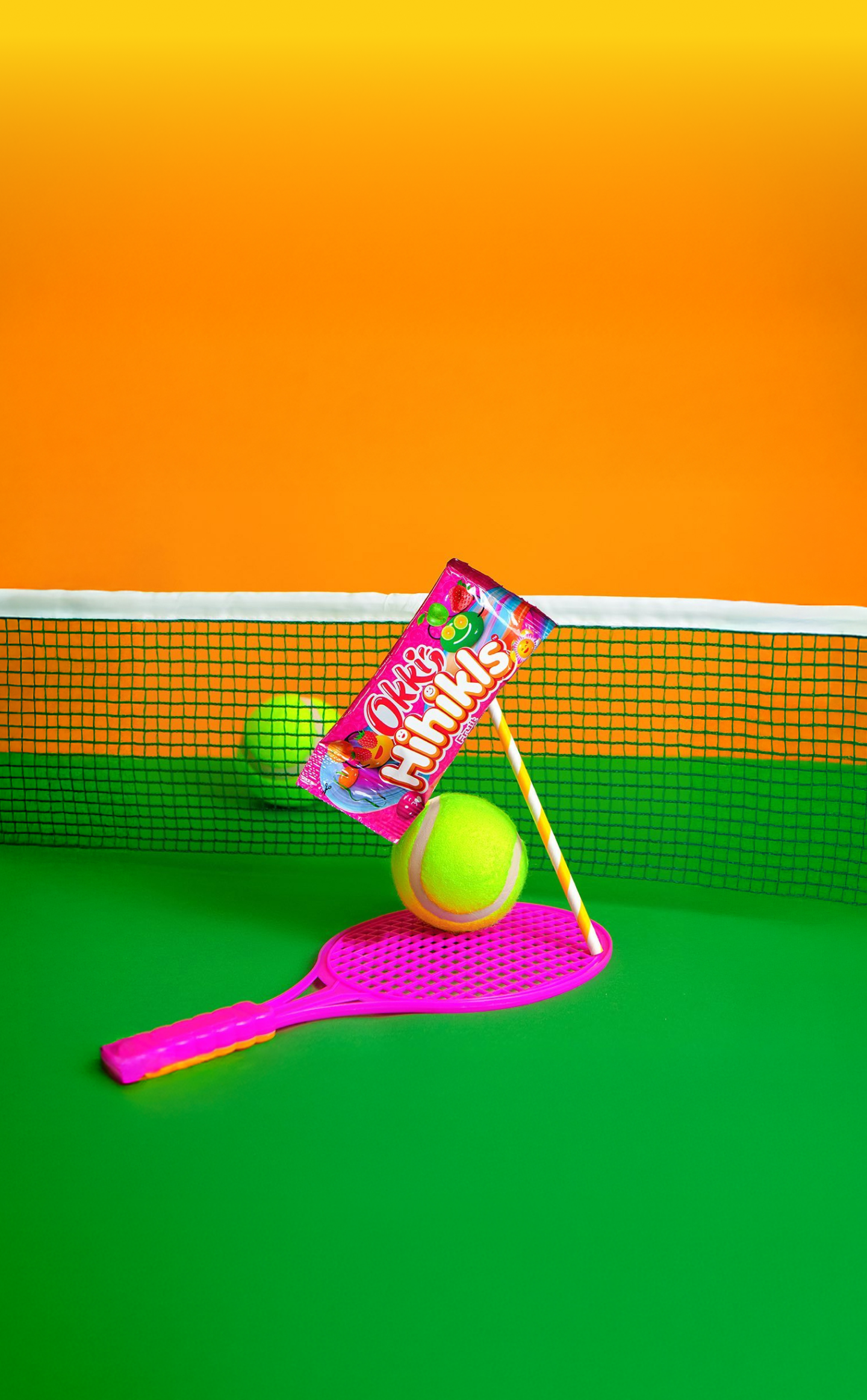 Okki candy pack balanced on a tennis ball and racket